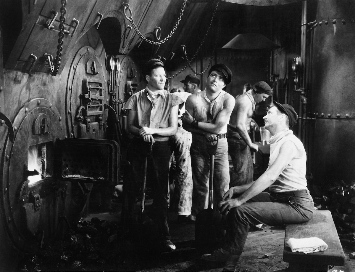 Labourers tending a large boiler furnace